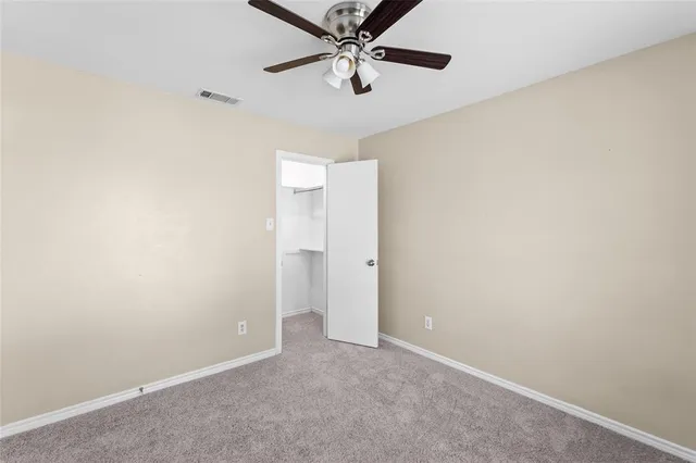 an empty room with a ceiling fan and carpet
