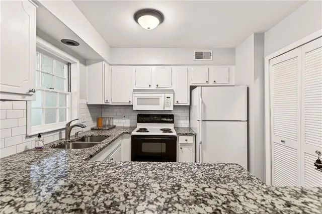 a kitchen with granite countertop a refrigerator sink stove and cabinets