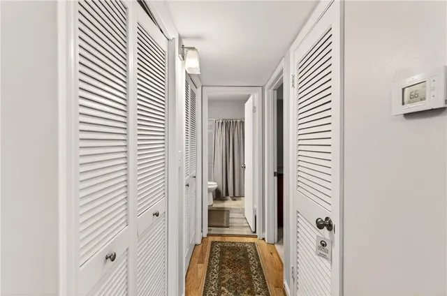 a view of a hallway with wooden floor and a bathroom
