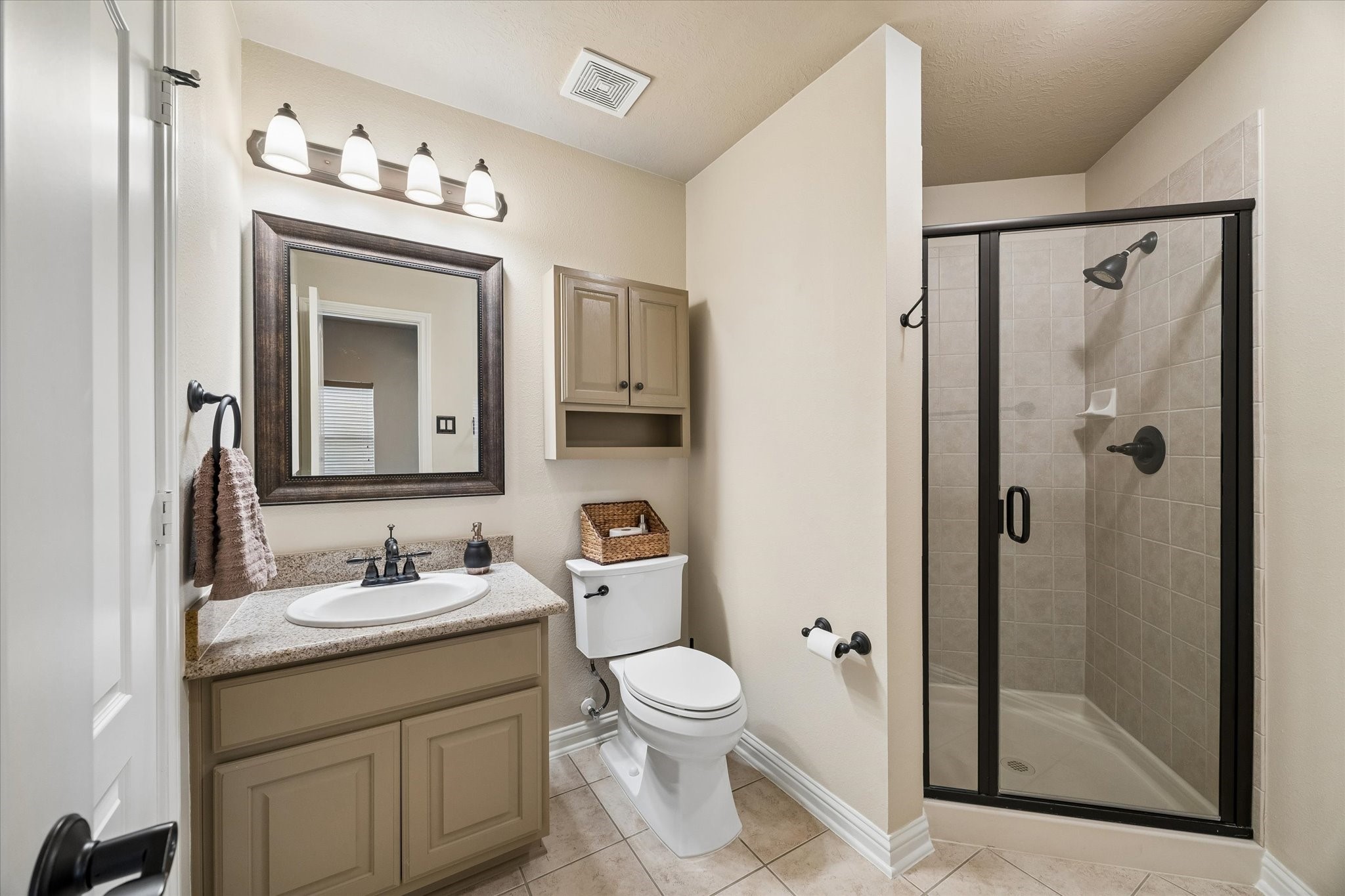 3902 Trailstone Lane Katy, TX 77494 - Photo 35 of 50 A full walk-in shower and a single sink vanity make this full bathroom ready from day one. With a framed mirror, over-the-john storage, and clean, crisp tile flooring, it offers a simple, functional space that is easy to enjoy every day.
