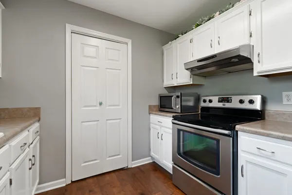 a kitchen with stainless steel appliances kitchen island granite countertop a refrigerator a stove and a sink with wooden floor