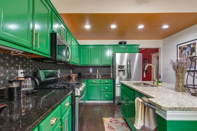 a kitchen with kitchen island granite countertop a sink a stove and a wooden cabinets