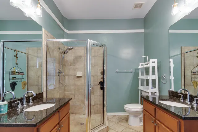 a bathroom with a granite countertop sink toilet a mirror a shower and vanity