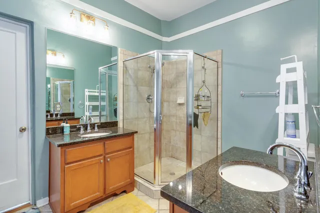 a bathroom with a sink double vanity granite tub shower and mirror