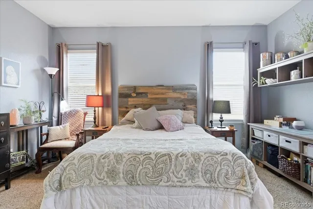 a bedroom with a bed a table and large window