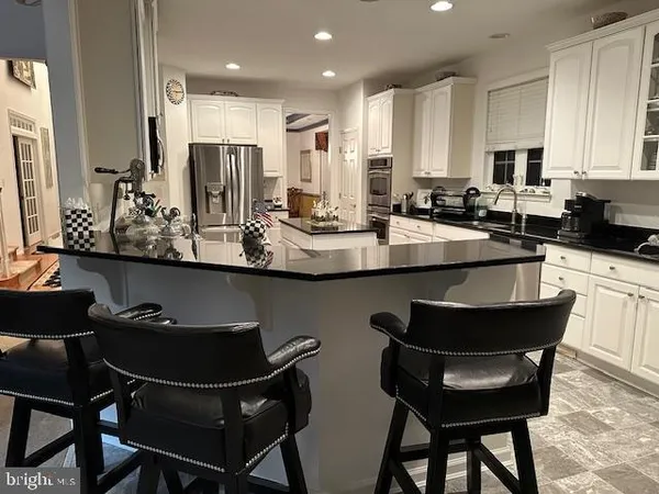 a kitchen with kitchen island granite countertop a sink and white cabinets