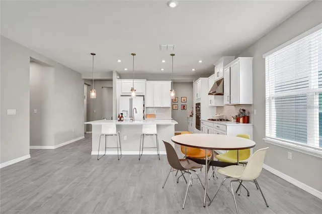 a living room with stainless steel appliances kitchen island a table and chairs in it