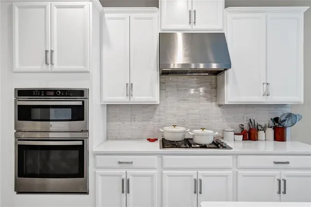 a kitchen with stainless steel appliances granite countertop white cabinets and a stove