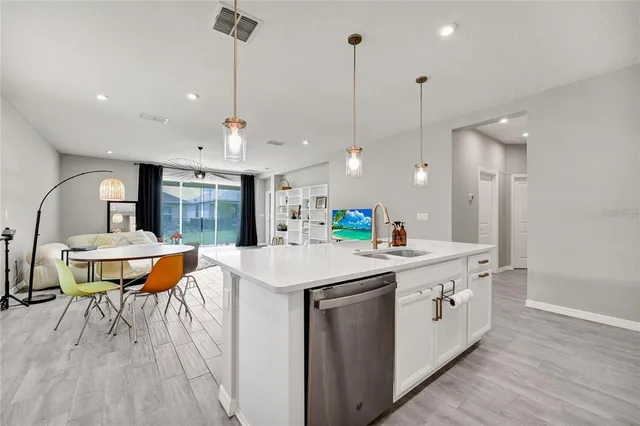 a kitchen with a sink a stove a dining table and chairs with wooden floor