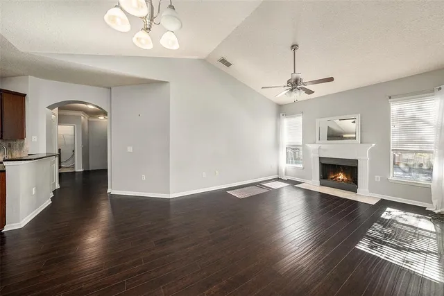 a view of an empty room with wooden floor fireplace and a window