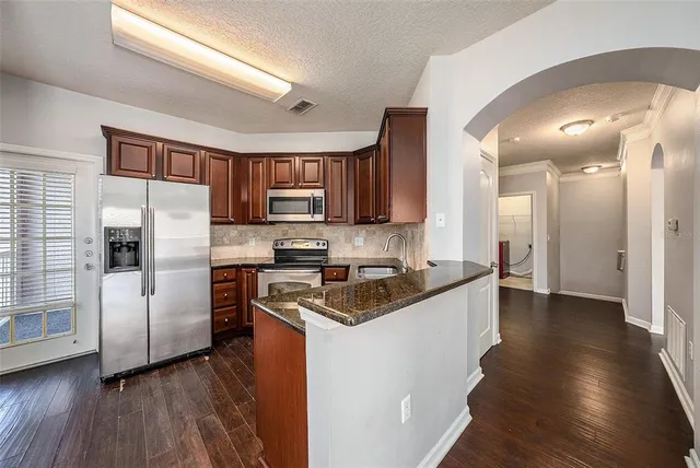 a kitchen with stainless steel appliances granite countertop a refrigerator a stove top oven a sink and dishwasher