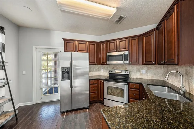 a kitchen with stainless steel appliances granite countertop a refrigerator stove top oven and sink