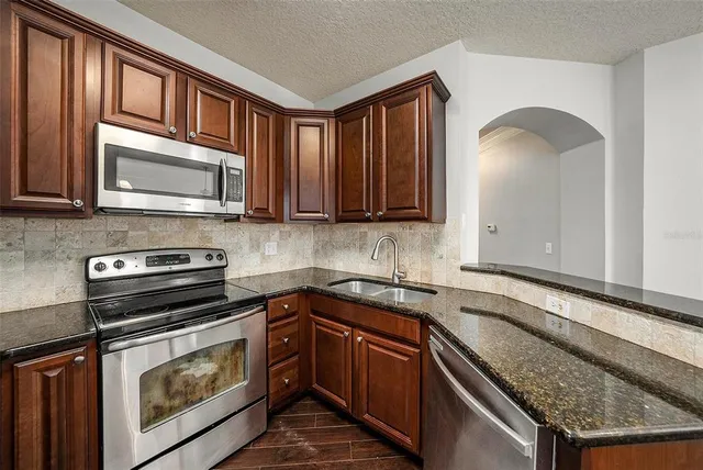 a kitchen with stainless steel appliances granite countertop a stove microwave and sink