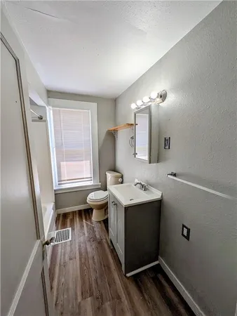 a bathroom with a sink a toilet a mirror and window