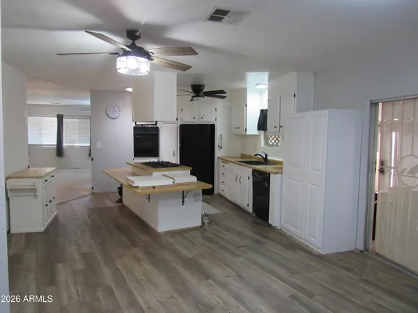 a living room with stainless steel appliances kitchen island hardwood floor and a view of kitchen