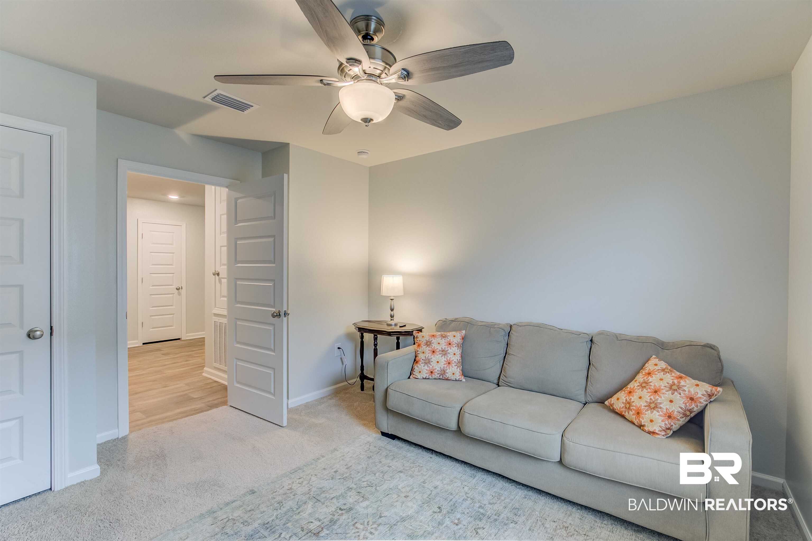 8033 Irwin Loop Daphne, AL 36526 - Photo 35 of 38 Carpeted room with a ceiling fan featuring integrated lighting, a contrasting light wood-finish flooring in the entryway, and white paneled doors with brushed nickel hardware