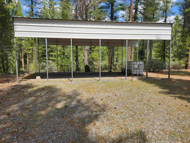 a backyard of a house with large trees and brick wall