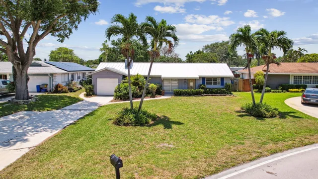 a front view of a house with garden and trees