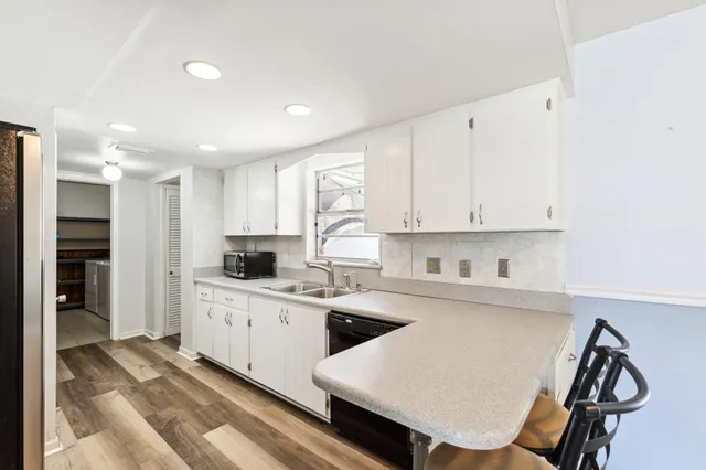 a kitchen with white cabinets and chairs