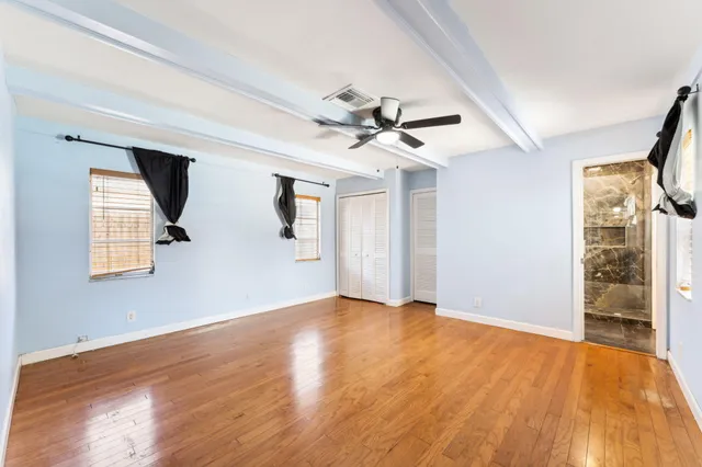a view of an empty room with window and wooden floor
