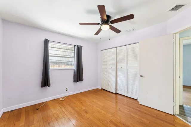 a view of empty room with wooden floor and fan