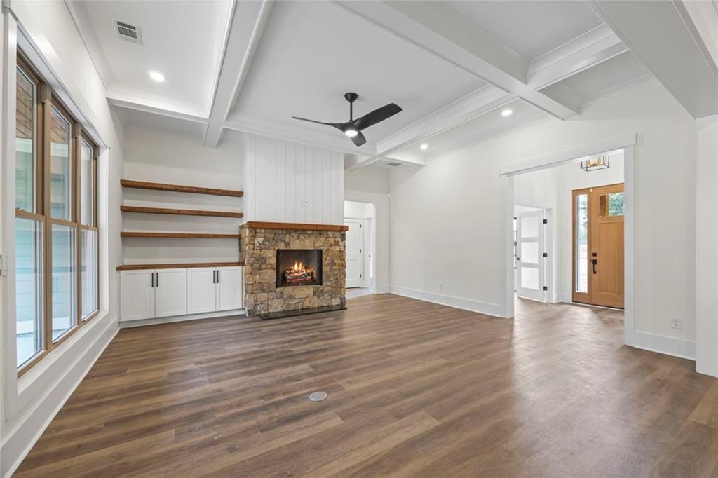 575 Hardy Road Martin, GA 30557 - Photo 8 of 16 an empty room with wooden floor a ceiling fan a fireplace and windows