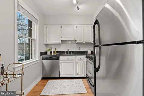 a kitchen with stainless steel appliances a refrigerator sink and white cabinets