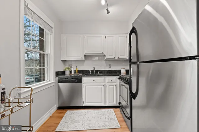 a kitchen with stainless steel appliances a refrigerator sink and white cabinets