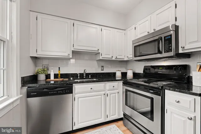 a kitchen with cabinets stainless steel appliances and a sink