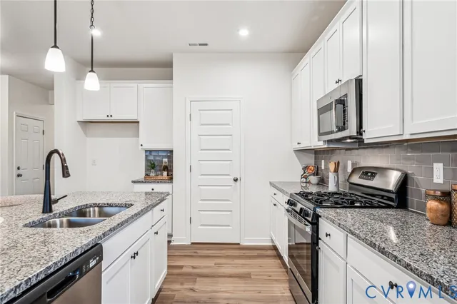 a kitchen with stainless steel appliances granite countertop a sink stove and cabinets