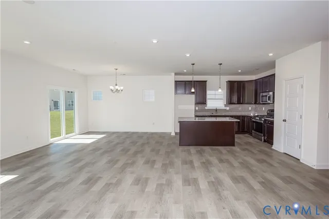 a large kitchen with kitchen island a sink dishwasher a stove and a refrigerator with wooden floor