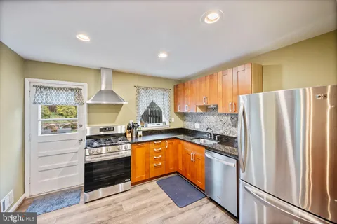 a kitchen with stainless steel appliances granite countertop a refrigerator a stove a sink and dishwasher with wooden floor