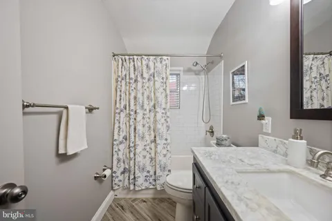 a bathroom with a granite countertop sink a toilet and shower
