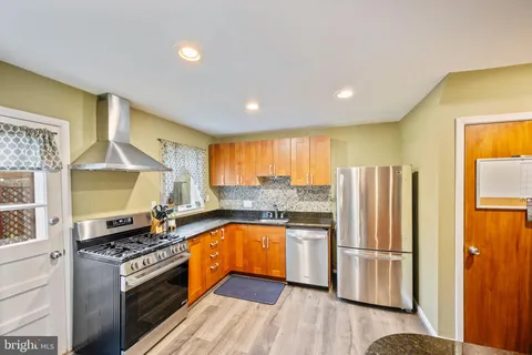 a kitchen with stainless steel appliances granite countertop a refrigerator a stove and a wooden floors