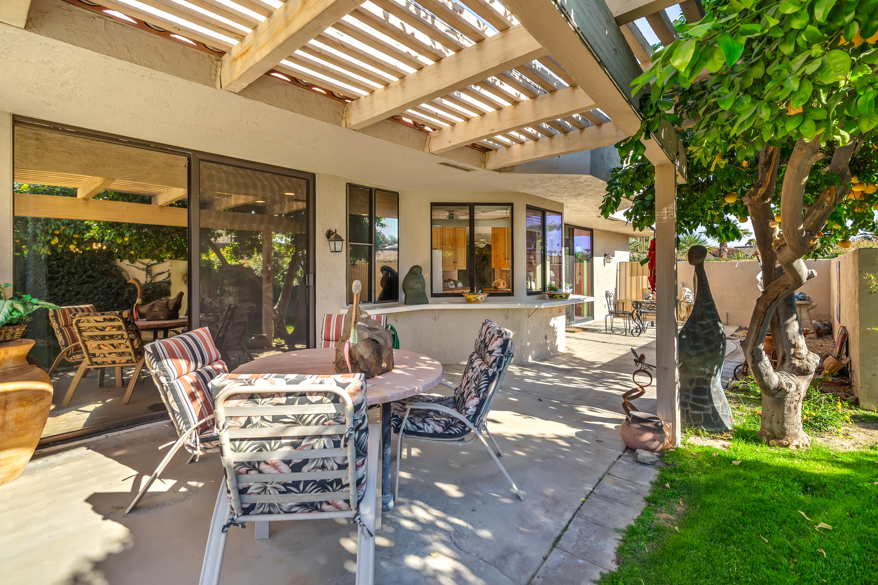 9 Swarthmore Court Rancho Mirage, CA 92270 - Photo 28 of 43 a view of a patio with table and chairs potted plants and large tree