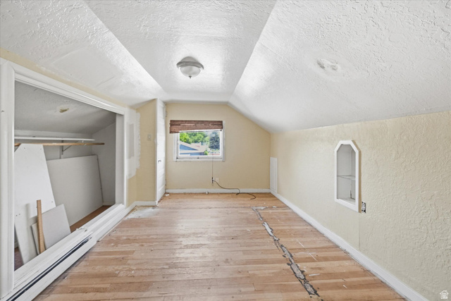 395 North 400 West Logan, UT 84321 - Photo 16 of 48 Attic room featuring sloped ceilings, exposed wood-finish flooring, a single window with blinds, and a built-in wall niche
