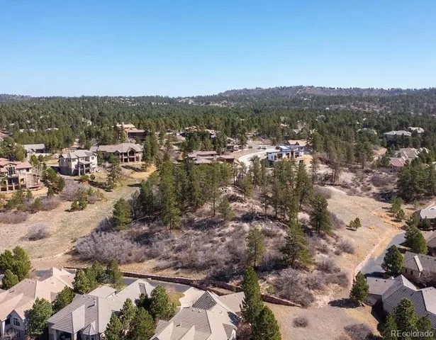 an aerial view of residential house with parking and trees