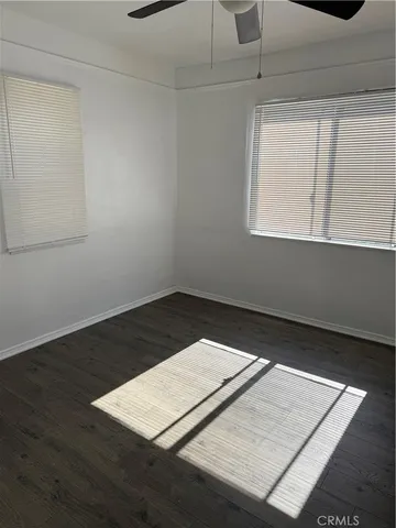 a view of an empty room with wooden floor and windows