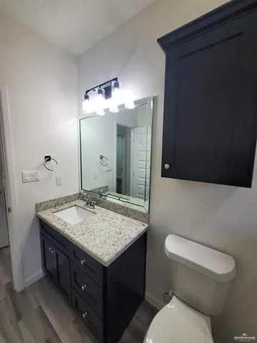 a bathroom with a granite countertop toilet sink and mirror