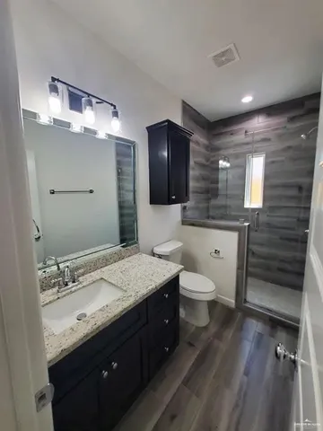 a spacious bathroom with a granite countertop sink toilet and mirror