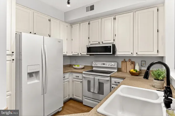 a kitchen with granite countertop white cabinets white stainless steel appliances and sink