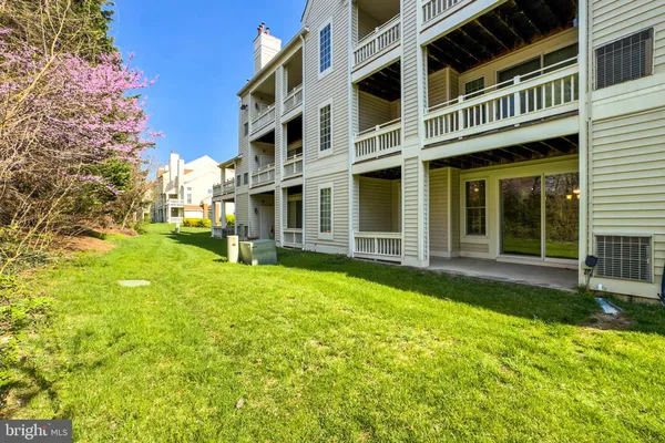 a view of a white house with large windows and a yard with plants