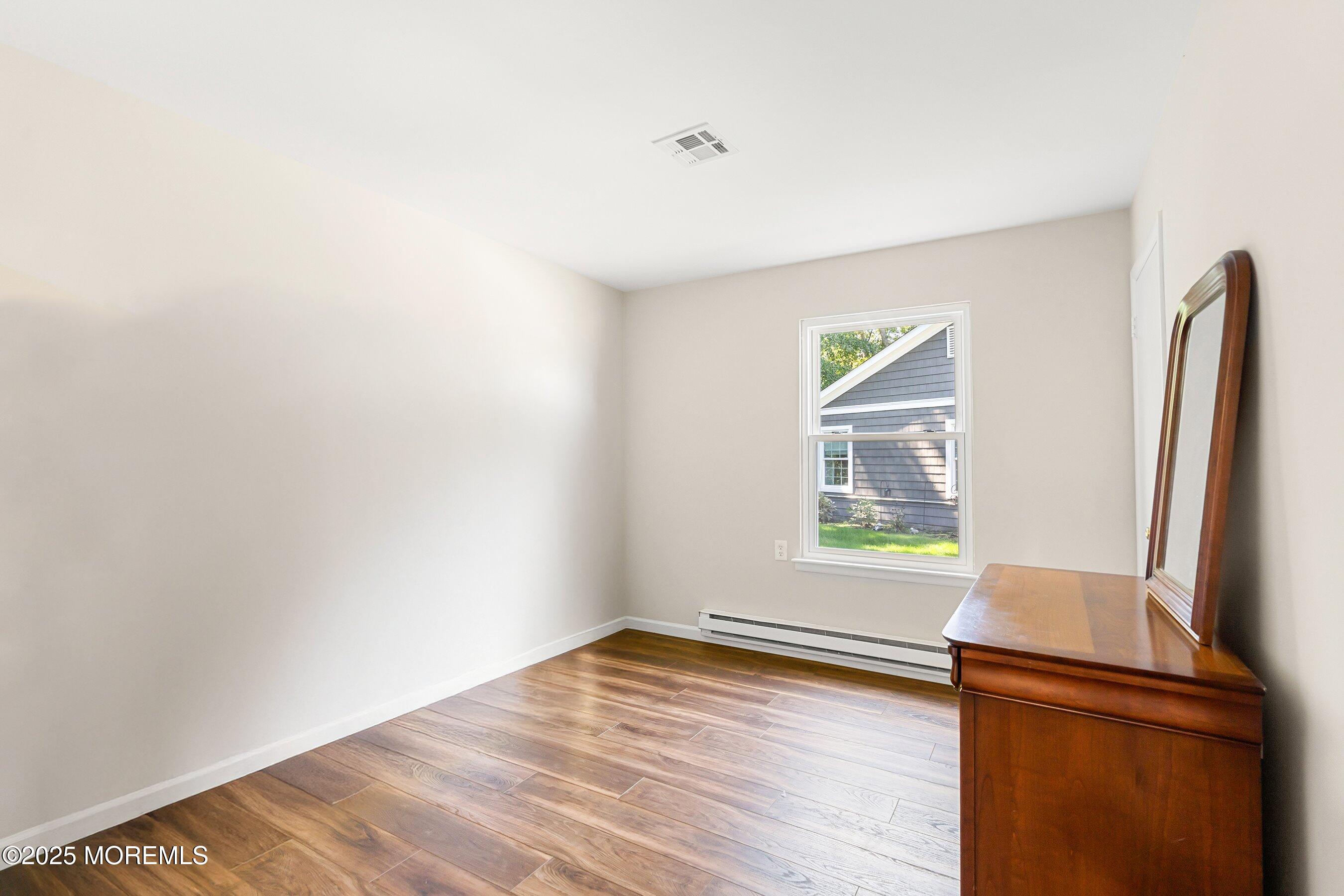 9 Whitney Court Brick, NJ 08724 - Photo 12 of 42 an empty room with wooden floor and a window