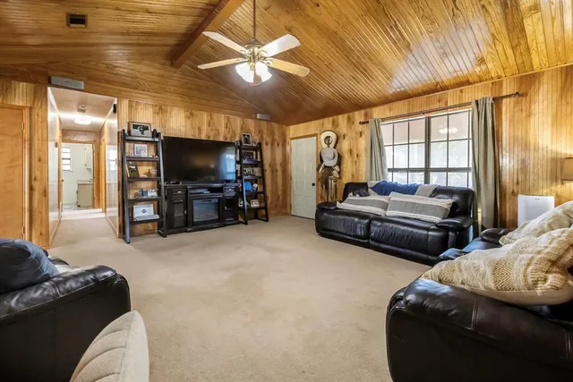 a living room with furniture a flat screen tv and ceiling fan