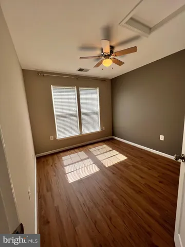 an empty room with wooden floor fan and windows