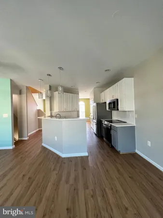 a view of kitchen with cabinets stainless steel appliances and wooden floor