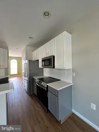 a kitchen with granite countertop a stove top oven a sink dishwasher and a refrigerator with wooden floor