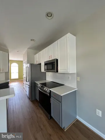 a kitchen with granite countertop a stove top oven a sink dishwasher and a refrigerator with wooden floor