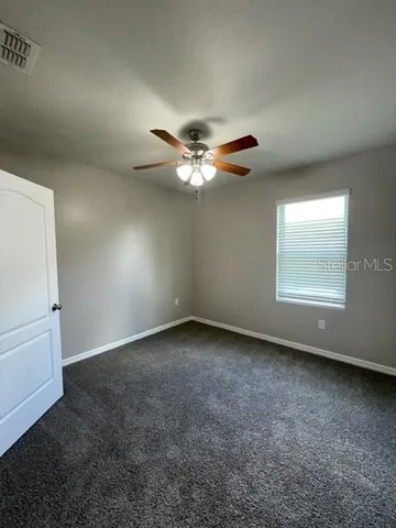 an empty room with windows and fan