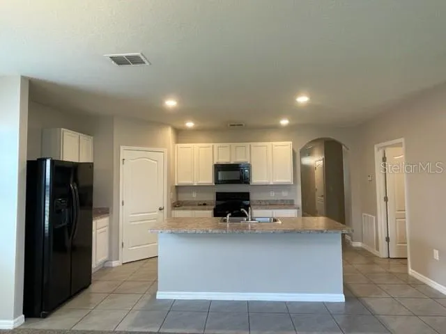 a view of kitchen with stainless steel appliances granite countertop a refrigerator and a sink